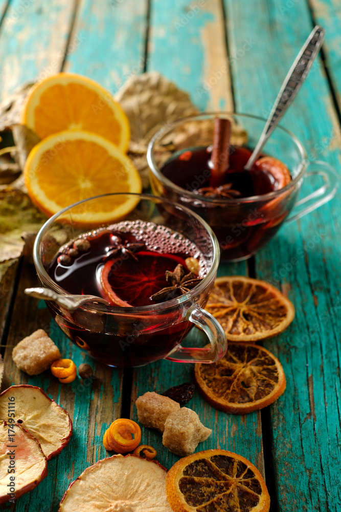 Hot mulled wine with orange, cinnamon, cardamom and anise on green wooden background Hot mulled wine with orange, cinnamon, cardamom and anise on green wooden background