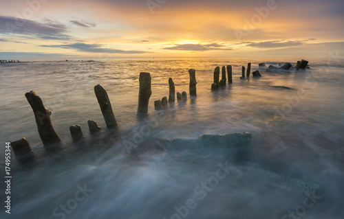 a sea breakwater breaking the waves at sunset