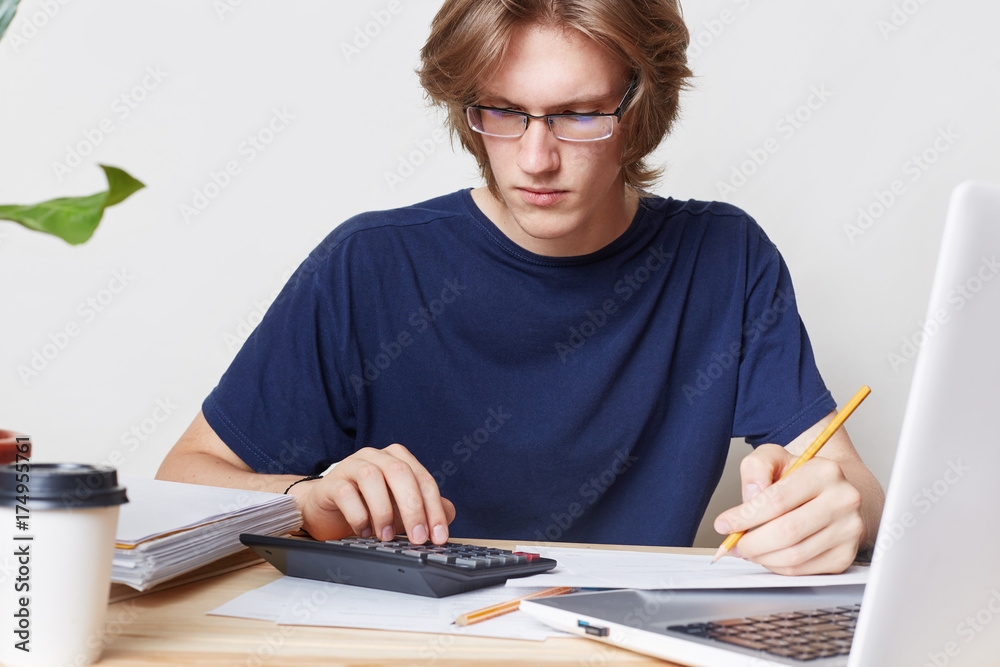 Attractive man faces financial crisis, studies notification from bank, calculates figures. Male student studies math, prepares report, calculates figures. People, business, occupation concept Attractive man faces financial crisis, studies notification from bank, calculates figures. Male student studies math, prepares report, calculates figures. People, business, occupation concept