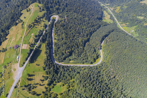Aerial view over mountain road going through forest landscape