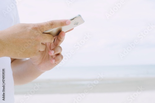 Young man wear plaid shirt. close up hand using on cell phone during rest on sofa. sitting in watching message on mobile smart phone during break relax. soft focus.