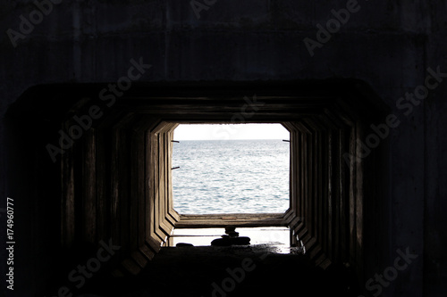 The Light at the End of the Tunnel. Technological tunnel of concrete slabs passes under the railway with access to the sea. photo