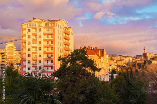 View of apartment buildings and trees on the background of beautiful cloudy sky at sunset, Sochi, Russia