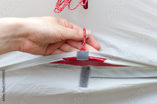 The girl opens a ventilation window in a tourist tent and fixes it with a velcro