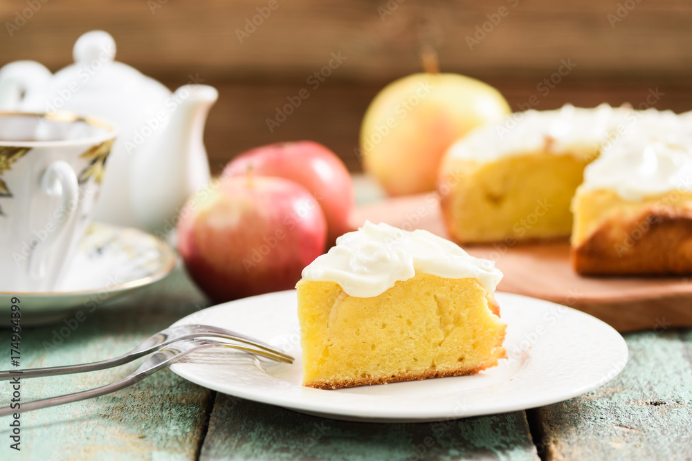 Homemade yummy cake with fluffy cream cheese icing served with tea and raw apples on shabby turquoise table