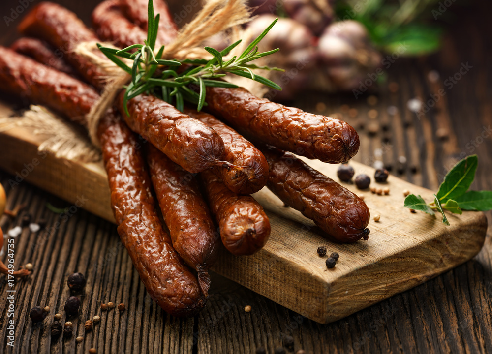 Kabanosy, polish sausages made of pork on a board with addition of fresh herbs and spices - obrazy, fototapety, plakaty 