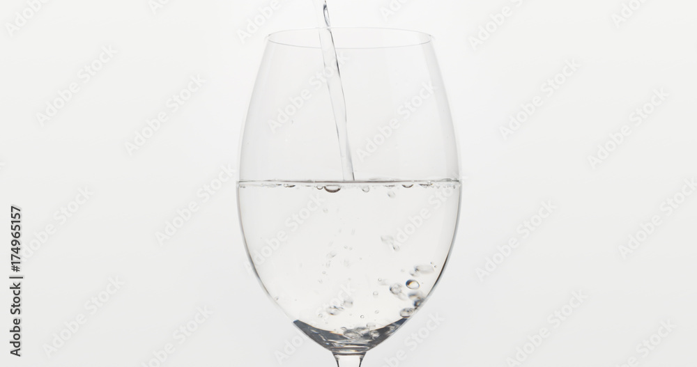 pouring water into wine glass over white background pouring water into wine glass over white background
