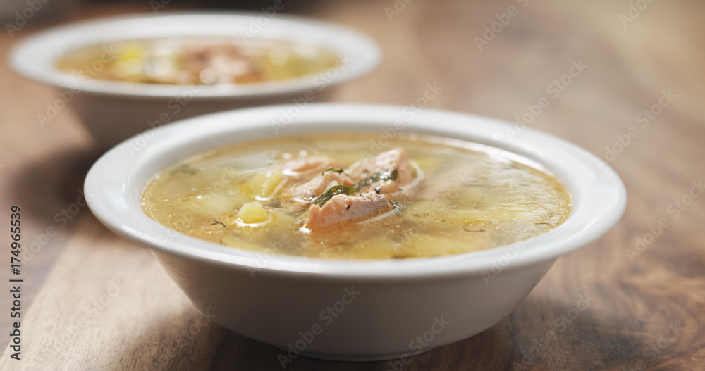 closeup seasoning with pepper fish soup with salmon on wood table