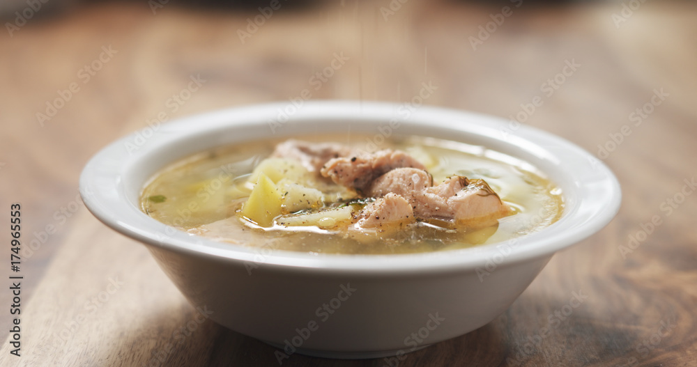 closeup seasoning with pepper fish soup with salmon on wood table closeup seasoning with pepper fish soup with salmon on wood table