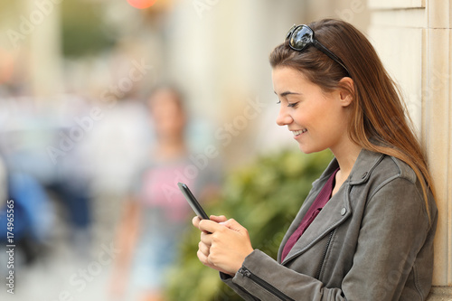 Profile of a fashion girl using a smart phone outside