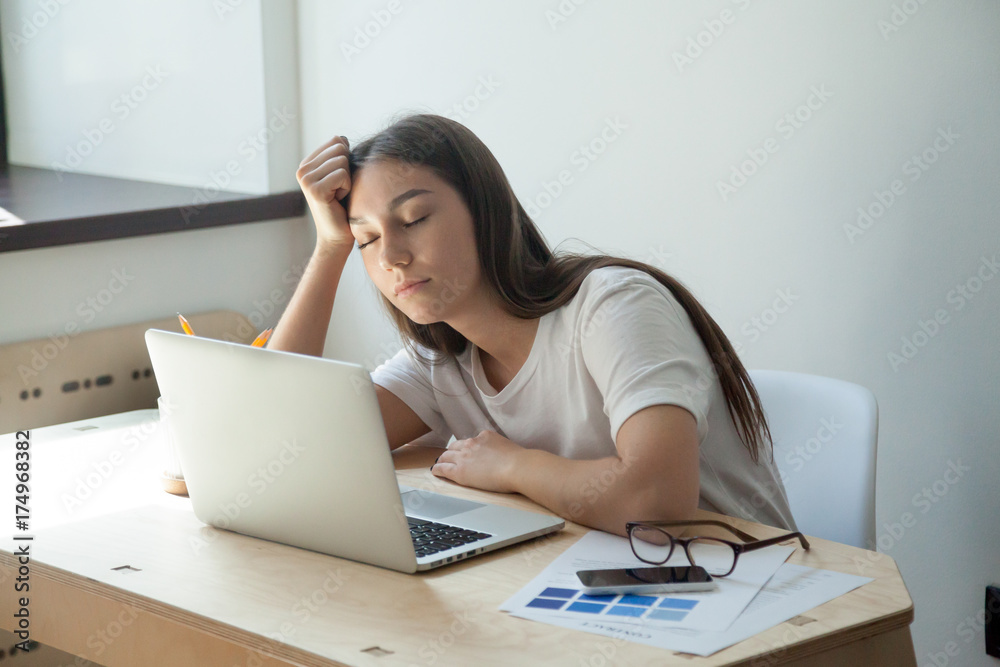 Young adult female designer sleeping on her desk, near her laptop computer and smartphone. She just finished color scheme for house interior renovation project and waits for customer review. Young adult female designer sleeping on her desk, near her laptop computer and smartphone. She just finished color scheme for house interior renovation project and waits for customer review.