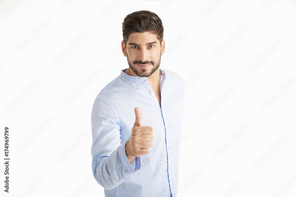It's okay. Smiling young man giving thumbs up while standing indoor. It's okay. Smiling young man giving thumbs up while standing indoor.