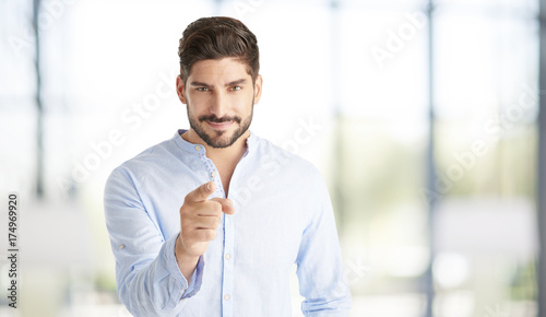 Hey you. Young sales businessman looking at you and pointing at the camera