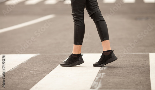 young woman crossing a street in the city on sunny summer day