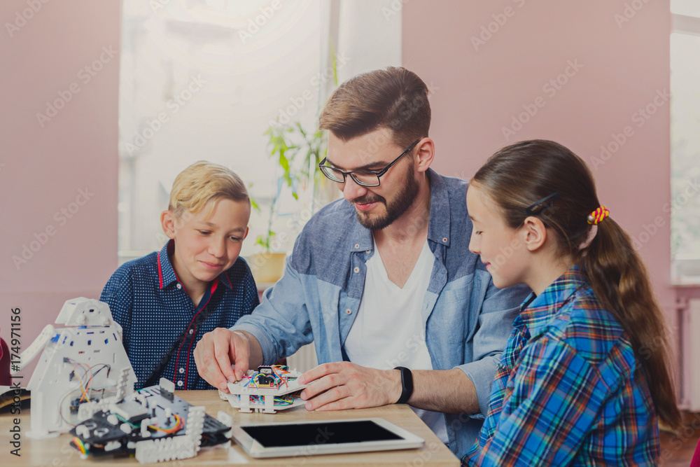 Fototapeta premium Stem education. Kids creating robots with teacher