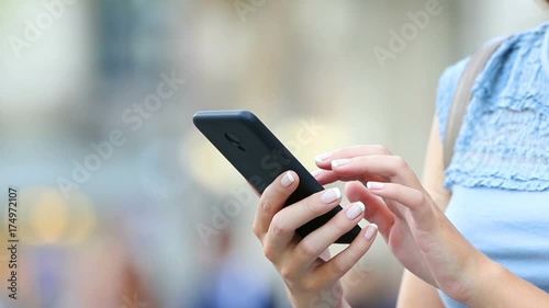 Close up of woman hands using a smart phone searching content on the street