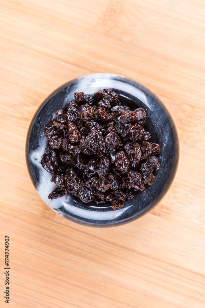 Black organic zante currants on a wood background