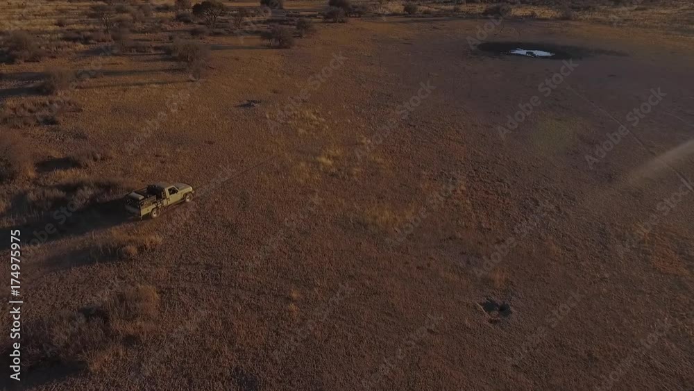 The SUV drives through the savannah to the puddle. The SUV drives through the savannah to the puddle.
