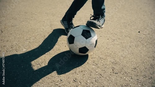 Children's Legs Play With A Soccerball On The Road