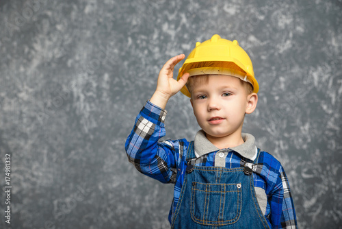 A boy holds onto a construction helmet and smiling