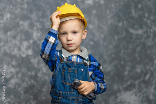 A boy holds onto a construction helmet and smiling © Sonya