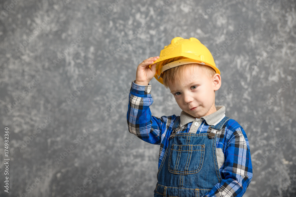 A boy holds onto a construction helmet and smiling