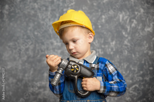 Boy in hard hat with drill, screwdriver in hand