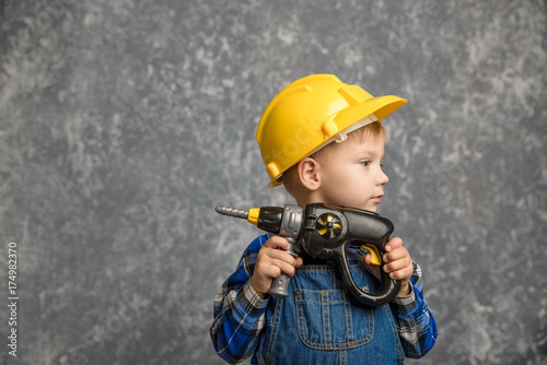 Boy in hard hat with drill, screwdriver in hand