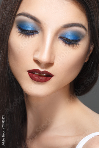 Fashion beauty portrait of a brunette girl with bright blue eye makeup.