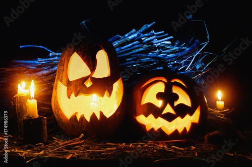 Photo for the holiday Halloween. Two evil pumpkins surrounded by candles on a dark background