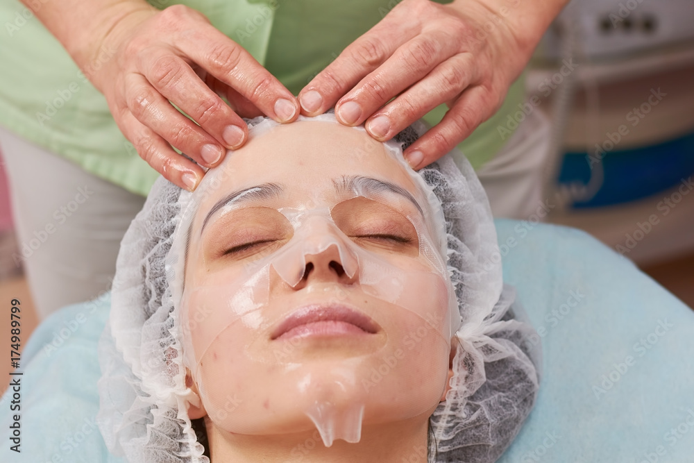 Hands applying facial hydrogel mask. Customer of cosmetologist. Hands applying facial hydrogel mask. Customer of cosmetologist.