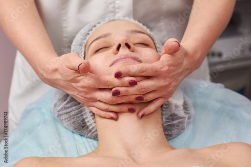 Hands massaging face  close up. Young woman  cosmetic facial massage.