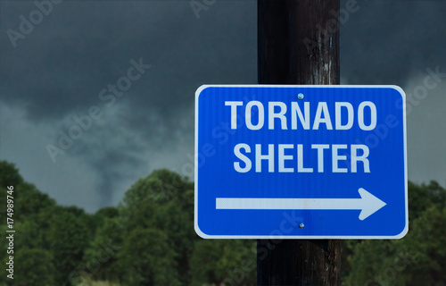 Tornado shelter sign with a small funnel cloud on background - concept for immediate danger in severe weather and seeking for shelter