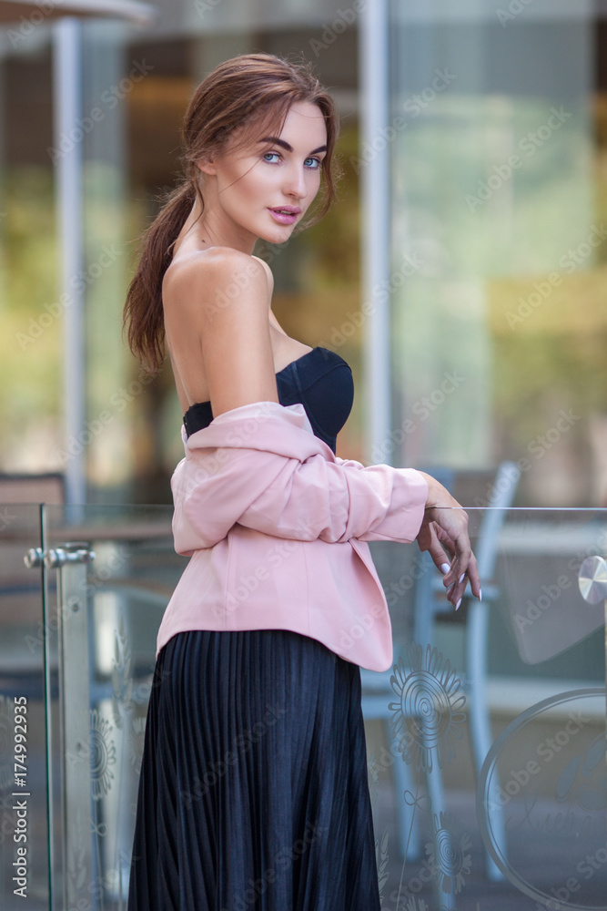 Young and fresh beautiful woman with naked shoulders in pleated skirt and  pink jacket outside. Stock Photo | Adobe Stock