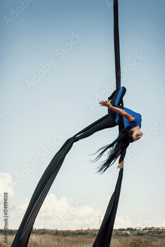 Elegance young beautiful woman dance with aerial silk on a sky background. Fly yoga sport 