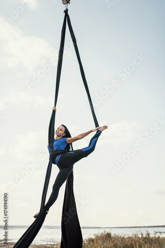 Elegance young beautiful woman dance with aerial silk on a sky background. Fly yoga sport 