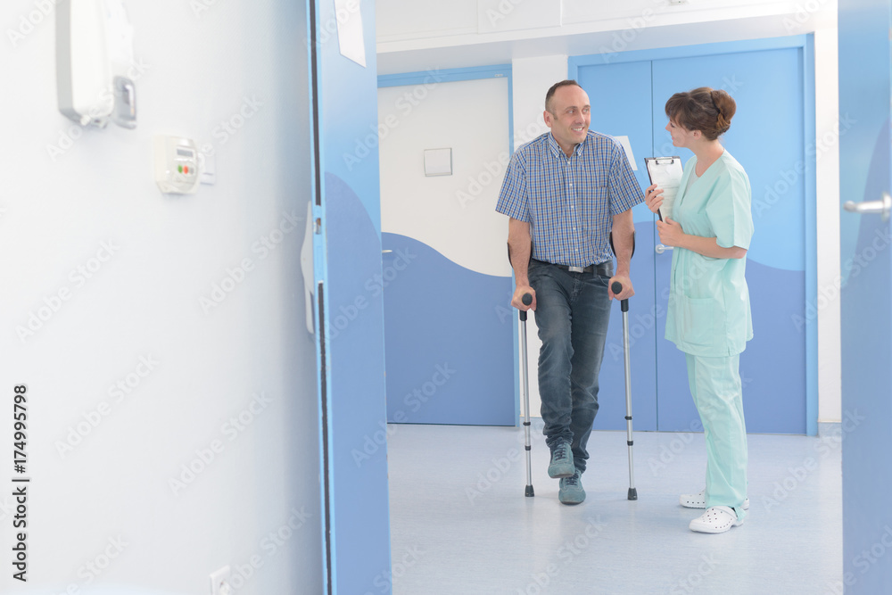 doctor talking to recovering mid age man with crutches doctor talking to recovering mid age man with crutches