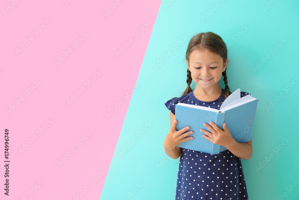 Cute little girl reading book on color background