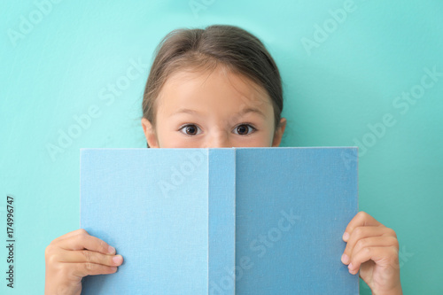 Cute little girl with book on color background © Africa Studio