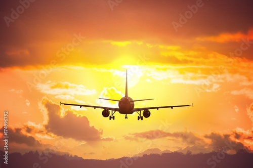 Silhouette of airplane flying in sunset.