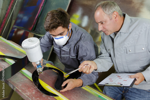 young man or worker in protective clothing with spray gun photo