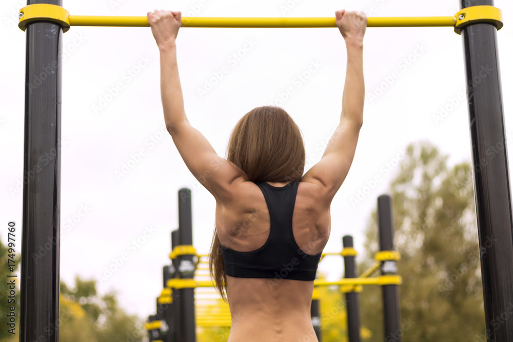 Fototapeta premium Fit woman exercising outdoors, healthy lifestyle and exercise concept. Pullups