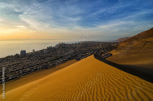 Stunning view to sand dunes, ocean and Iquique city at sunset photo