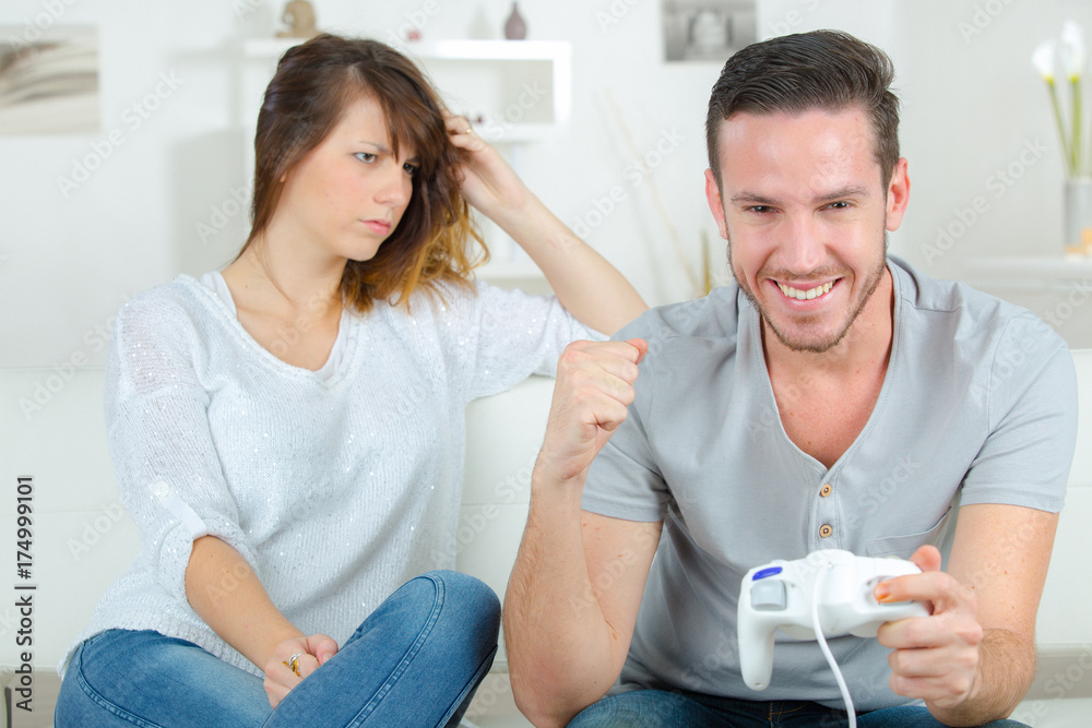 Irritated woman watching man play computer game Irritated woman watching man play computer game