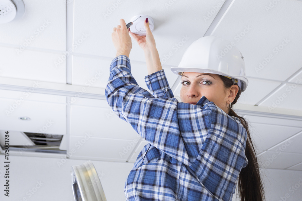 female worker installing smoke detector at home female worker installing smoke detector at home