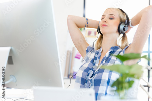 Young woman listening to the music while working on a computer