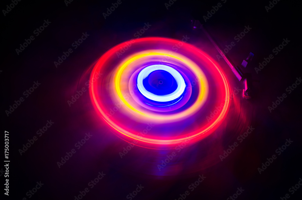 Turntable playing vinyl with glowing abstract lines concept on dark background. Selective focus Turntable playing vinyl with glowing abstract lines concept on dark background. Selective focus