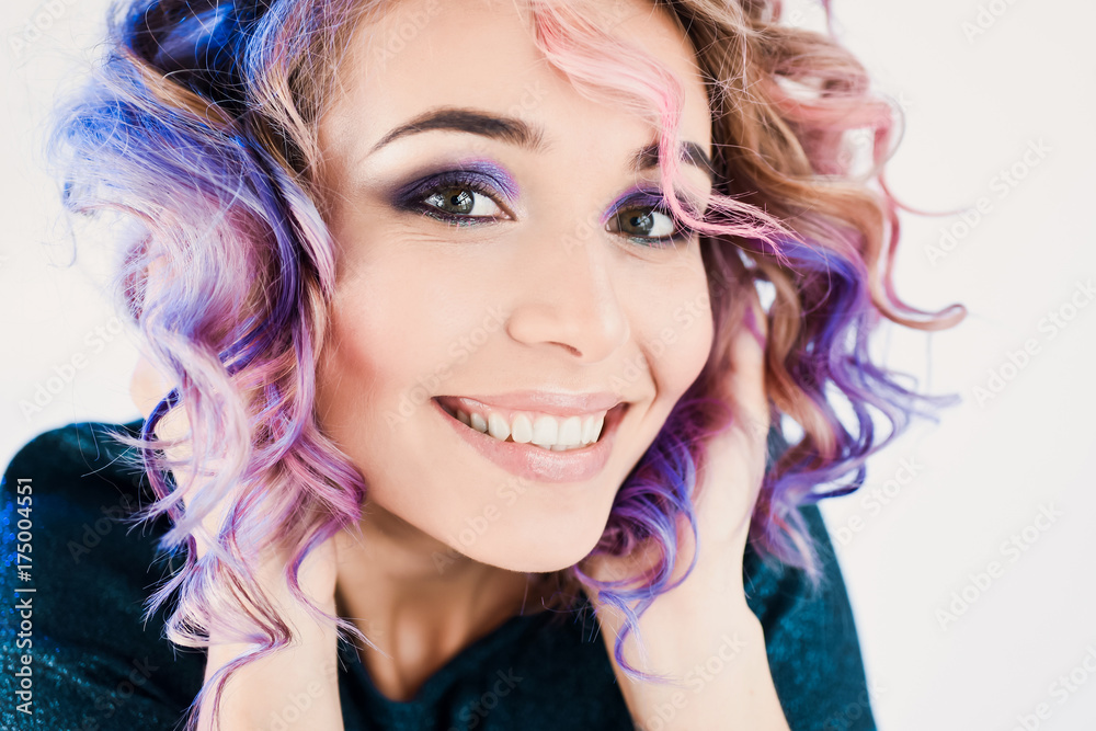 close-up portrait in studio isolated beautiful sexy young blond hipster girl with lilac and pink hair posing with tooth smile with smartphone in hands