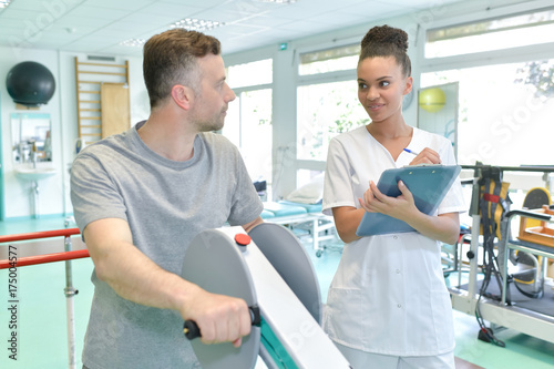Physiotherapist observing patient using equipment