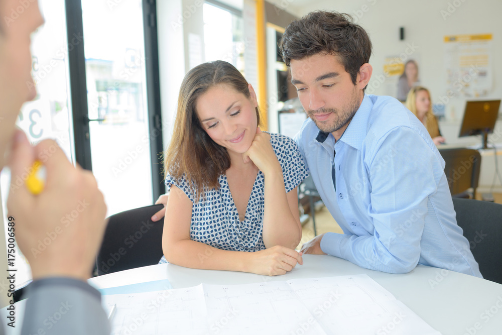 Fototapeta premium Couple with estate agent looking at blueprints